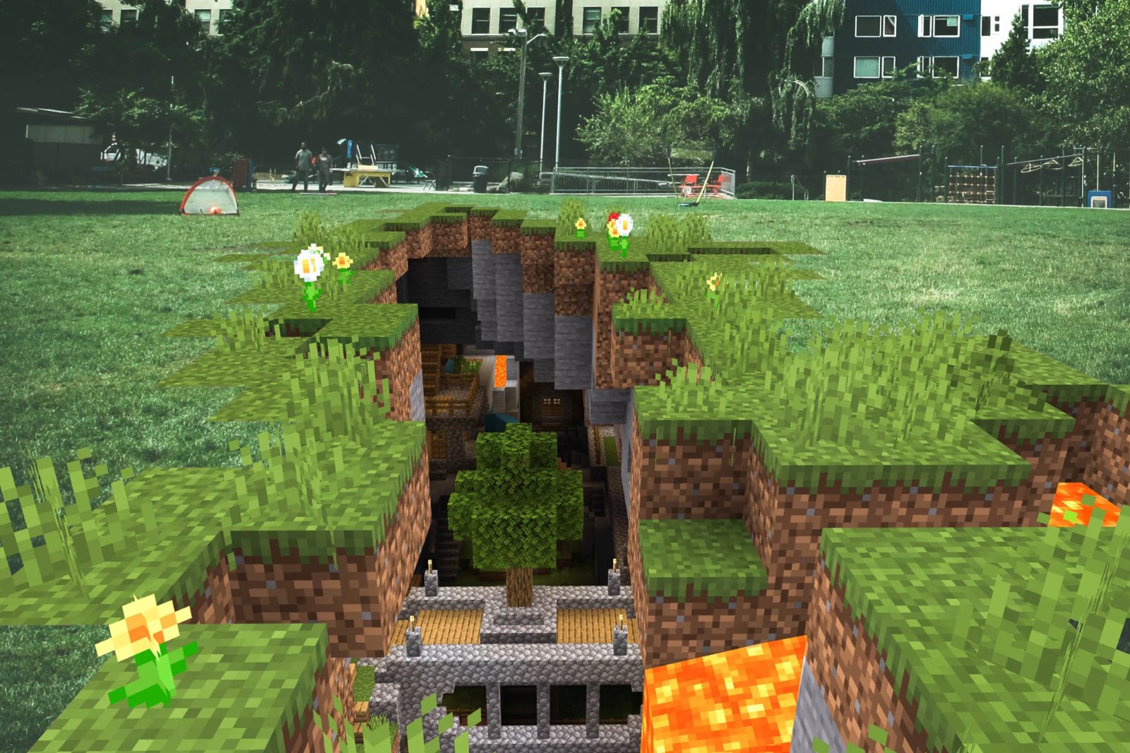 A first-person Minecraft landscape with grass, flowers, water, a cave, and exposed lava.